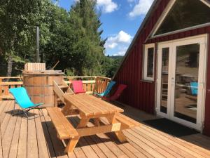 eine Holzterrasse mit einem Picknicktisch und Stühlen in der Unterkunft Chambre d'hôtes Carélie et Laponie in Orbey