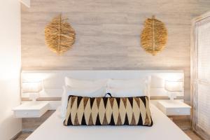 1 dormitorio con 1 cama blanca y 2 mesas blancas en Vila Baleira Suites, en Porto Santo