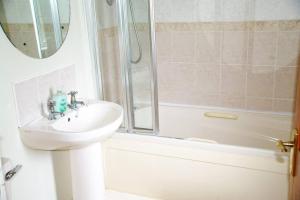 y baño blanco con lavabo y ducha. en Cosy & convenient beach retreat, en Tramore