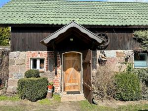 dom z drewnianymi drzwiami i zielonym dachem w obiekcie Apartament Loftowy- Bory Tucholskie w mieście Świekatowo