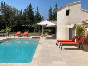una piscina con sillas rojas y una casa en Villa Rochefort-du-Gard proche Avignon, en Rochefort-du-Gard