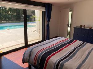 een slaapkamer met een bed en een groot raam met een zwembad bij Villa Rochefort-du-Gard proche Avignon in Rochefort-du-Gard