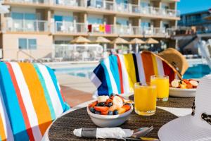 a table with a bowl of fruit and glasses of orange juice at Reges Oceanfront Resort in Wildwood Crest