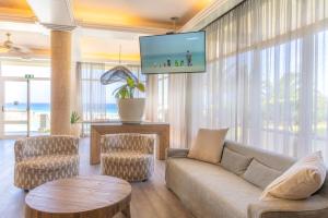 a living room with a couch and a flat screen tv at Vila Baleira Suites in Porto Santo