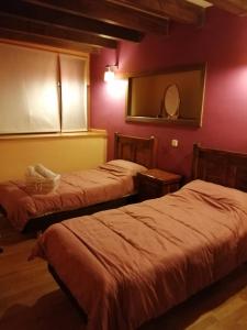 two beds in a room with red walls at Caballito de Madera in Pelegrina