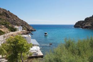 a boat in the water next to a beach at MASTIHA SeaSide Emporios Apartments in Emporeiós