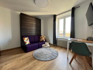uma sala de estar com um sofá roxo e uma secretária em Auberge de la Pétrusse em Luxemburgo