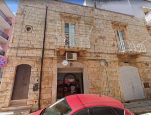 un bâtiment en briques avec une voiture rouge garée devant lui dans l'établissement La finestra sulla Puglia, à Castellana Grotte