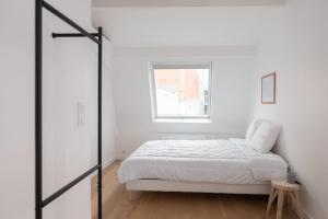 a white bedroom with a bed and a window at Bright duplex near the center of Vincennes in Montreuil