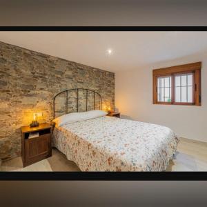 a bedroom with a bed and a stone wall at Fuente Vieja in Cortegana