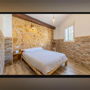 a bedroom with a bed and a brick wall at Fuente Vieja in Cortegana +9 photos