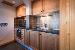 a kitchen with wooden cabinets and a sink at Le Dahu - 8-kamer chalet + sauna & bar 14 personen in Landry