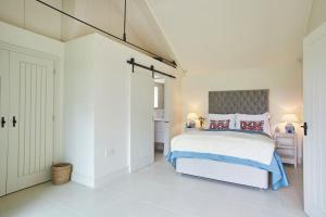 a white bedroom with a large bed with red pillows at The Garden House - Luxurious bolthole near coast in Banningham