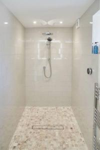 a white bathroom with a shower and a tile floor at The Garden House - Luxurious bolthole near coast in Banningham