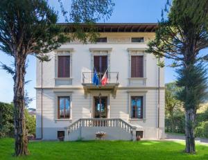a large white house with a balcony and two flags at Villa Ricci Suites in Lucca