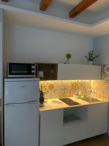 La cuisine est équipée d'un réfrigérateur blanc et d'un four micro-ondes. dans l'établissement Caelum Case Vacanza, à Trapani
