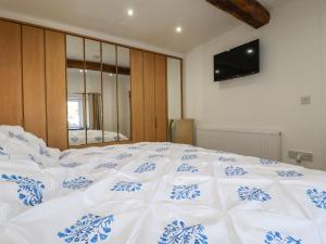 a large white bed with a blue and white comforter at Harvenna Cottage in Bude