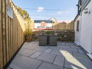 a patio with a fence and a sign on a building at Harvenna Cottage in Bude