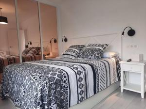 a large bed with a black and white comforter and pillows at Soleado apartamento con garaje in Santander