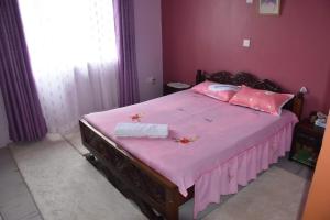 Un dormitorio con una cama rosa con sábanas y almohadas rosas. en 3-bedroom, 2-bedroom, 1-bedroom serenity homes en Langata Rongai