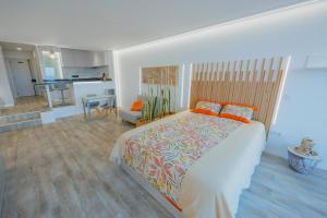 a bedroom with a large bed and a kitchen at Sea Breeze III in Caniço
