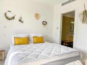 een slaapkamer met een groot wit bed met gele kussens bij Marion - Plage à pied, Clim, Wifi - Agosta in Albitreccia
