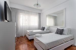 a white living room with a couch and a mirror at Sofisticado em Copacabana - 2 Suites - A801 in Rio de Janeiro