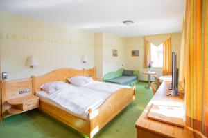 a bedroom with a bed and a chair and a television at Hotel-Pension Eschwege in Eschwege