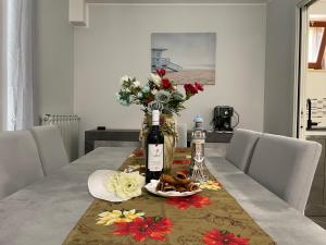 una mesa de comedor con una botella de vino y flores en Residenza Punta Acquabella en Ortona