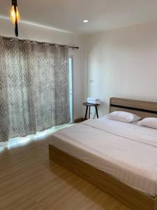 um quarto com uma cama grande e uma janela em Thanyaporn Guest House - Don Mueang em Thung Si Kan