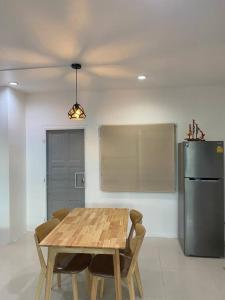 uma cozinha com uma mesa de madeira e um frigorífico em Thanyaporn Guest House - Don Mueang em Thung Si Kan