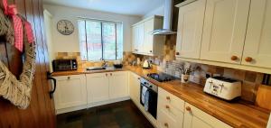 a kitchen with white cabinets and a wooden counter top at Vale View Cottages - The Stables in Prestatyn