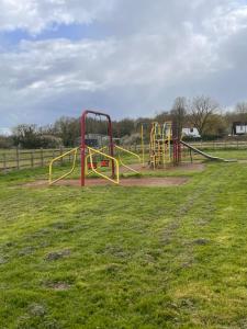 a playground with a yellow and red slide in a field at Prelude Guesthouse, Brigsley Grimsby in Grimsby