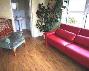 a living room with a red couch and a chair at Ashton Beach House in Tramore