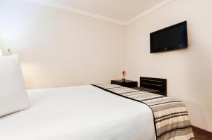 1 dormitorio con 1 cama blanca y TV de pantalla plana en Exe Cristal Palace, en Barcelona
