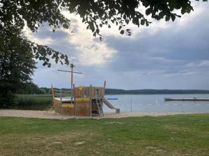 a playground with a slide next to a body of water at gemütliches Holzhaus am See in Warin