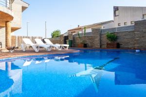 uma piscina com espreguiçadeiras brancas ao lado de um edifício em Villa Luxury Rock Tirri em Reus