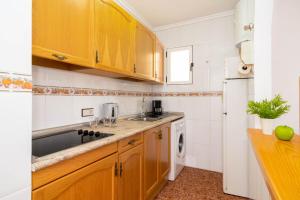 a kitchen with wooden cabinets and a sink and a dishwasher at Apartamentos Villa Madrid in Torrevieja
