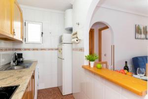 a kitchen with white walls and a counter with fruit on a shelf at Apartamentos Villa Madrid in Torrevieja