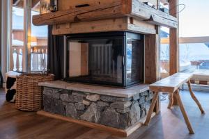 a stone fireplace in a living room with a bench at L'ourse et L'ange - Luxury chalet (8p). 3 bedrooms, 2 bathrooms and a loft. In the centre of Vallandry, with ski-in & out in Landry