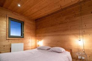1 dormitorio con 1 cama en una pared de madera en L'ourse et L'ange - Luxury chalet (8p). 3 bedrooms, 2 bathrooms and a loft. In the centre of Vallandry, with ski-in & out, en Landry