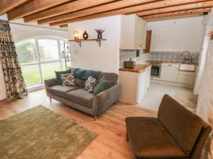 a living room with a couch and a kitchen at Abaty Cottage in Haverfordwest