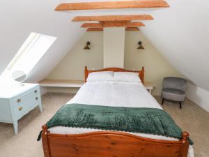 a bedroom with a wooden bed and a chair at Abaty Cottage in Haverfordwest