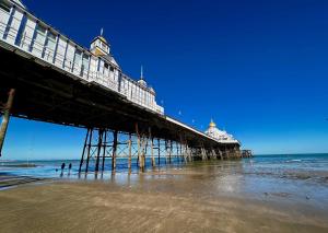 a pier with people standing on the beach near the water at Pearl & Pebbles Eastbourne in Eastbourne