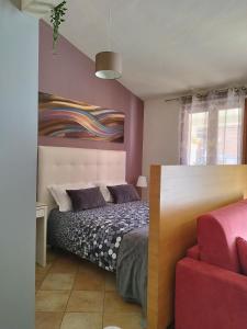 1 dormitorio con 1 cama y una pintura en la pared en Casa Nicole, en Castelbuono
