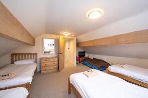 a attic room with three beds and a dresser at Chestnut Barn, North Norfolk with private hot tub & close to beaches in Norwich