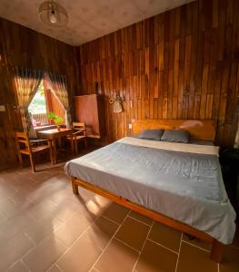 a bedroom with a bed and a wooden wall at Wooden style bungalow have kitchen in Phu Quoc
