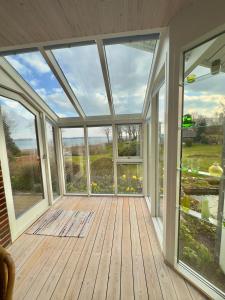 un porche acristalado vacío con ventanas grandes en Værelse med udsigt over Limfjorden - rolige omgivelser og adgang til flot have en Nykøbing Mors