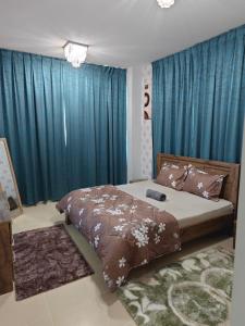 a bedroom with a large bed with blue curtains at Diamond Room in Shared Apartment in Ajman 