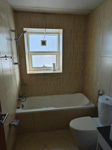 a bathroom with a tub and a toilet and a window at Diamond Room in Shared Apartment in Ajman 